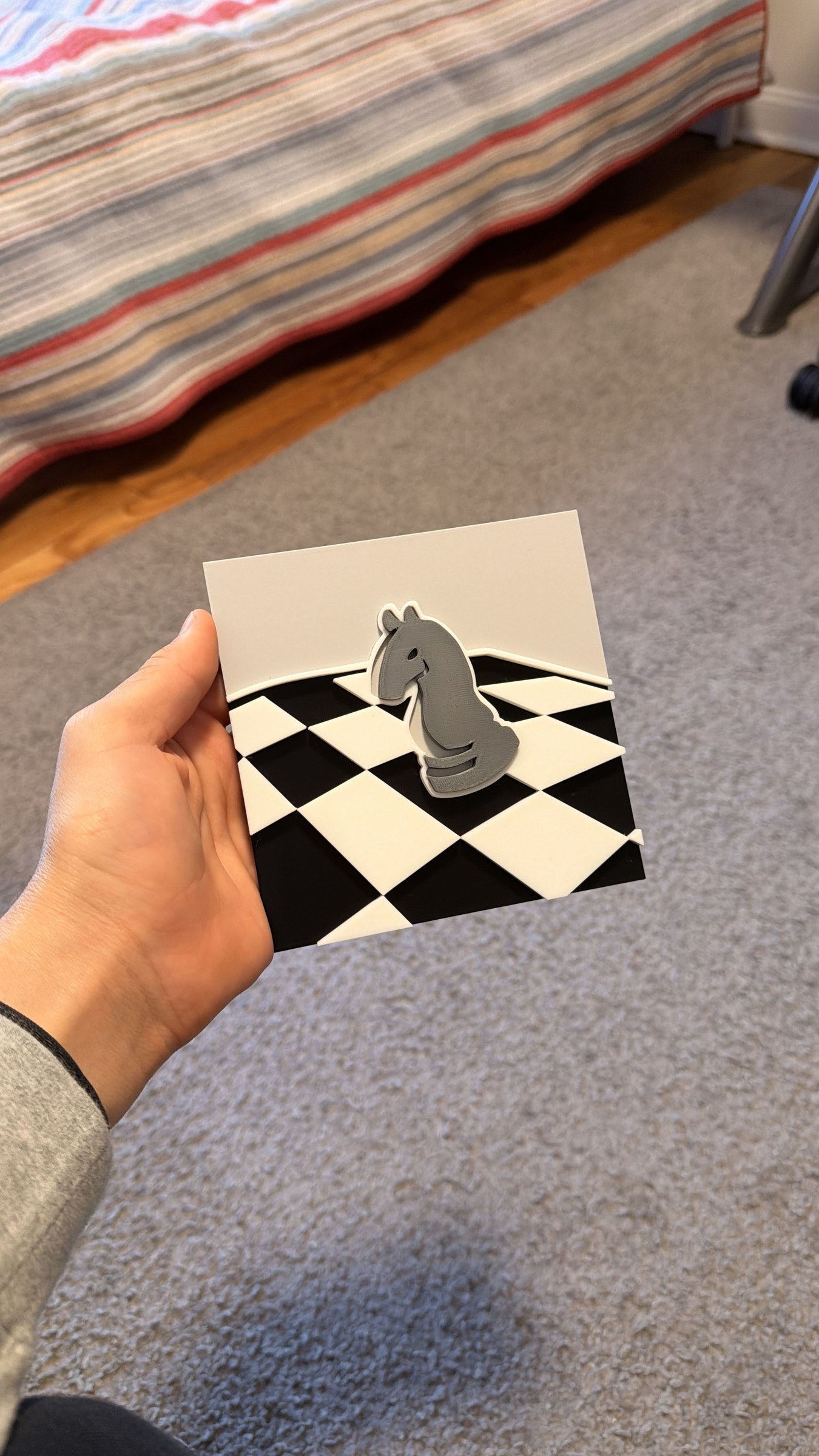 A hand holds a dimensional chess Passion Window prototype.