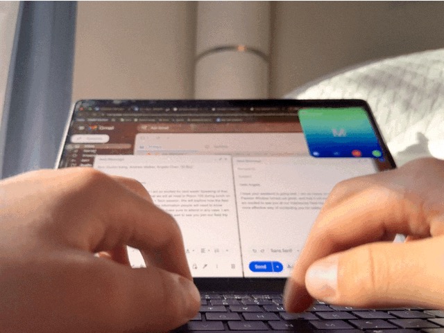 Hands writing an email during a call—coordination as part of the creative process.